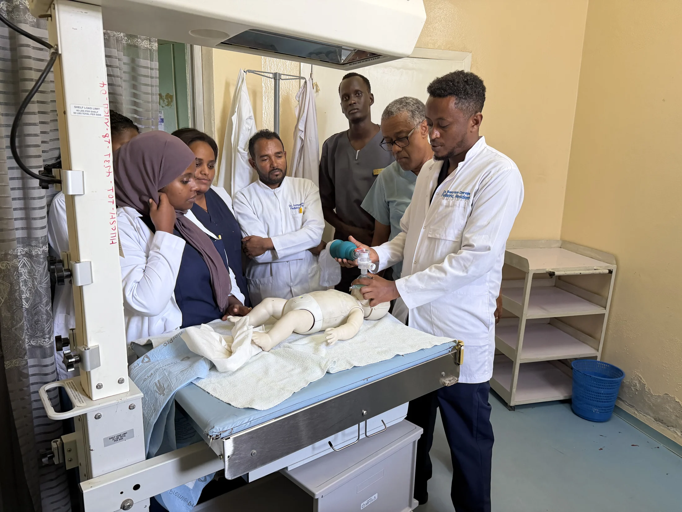 Medical professionals practicing neonatal care with a training mannequin